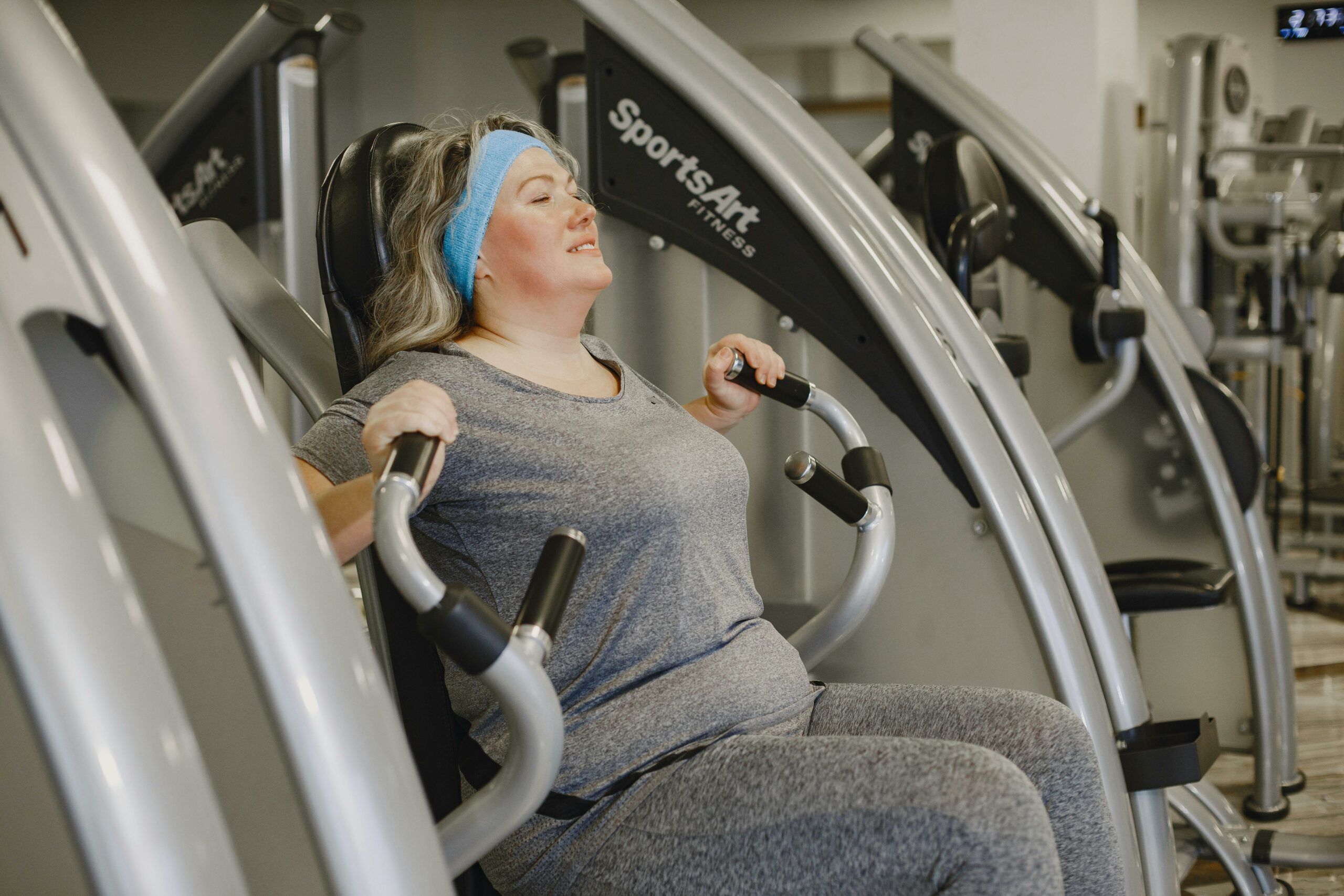 Plus size woman working out on gym equipment indoors, promoting health and wellness.